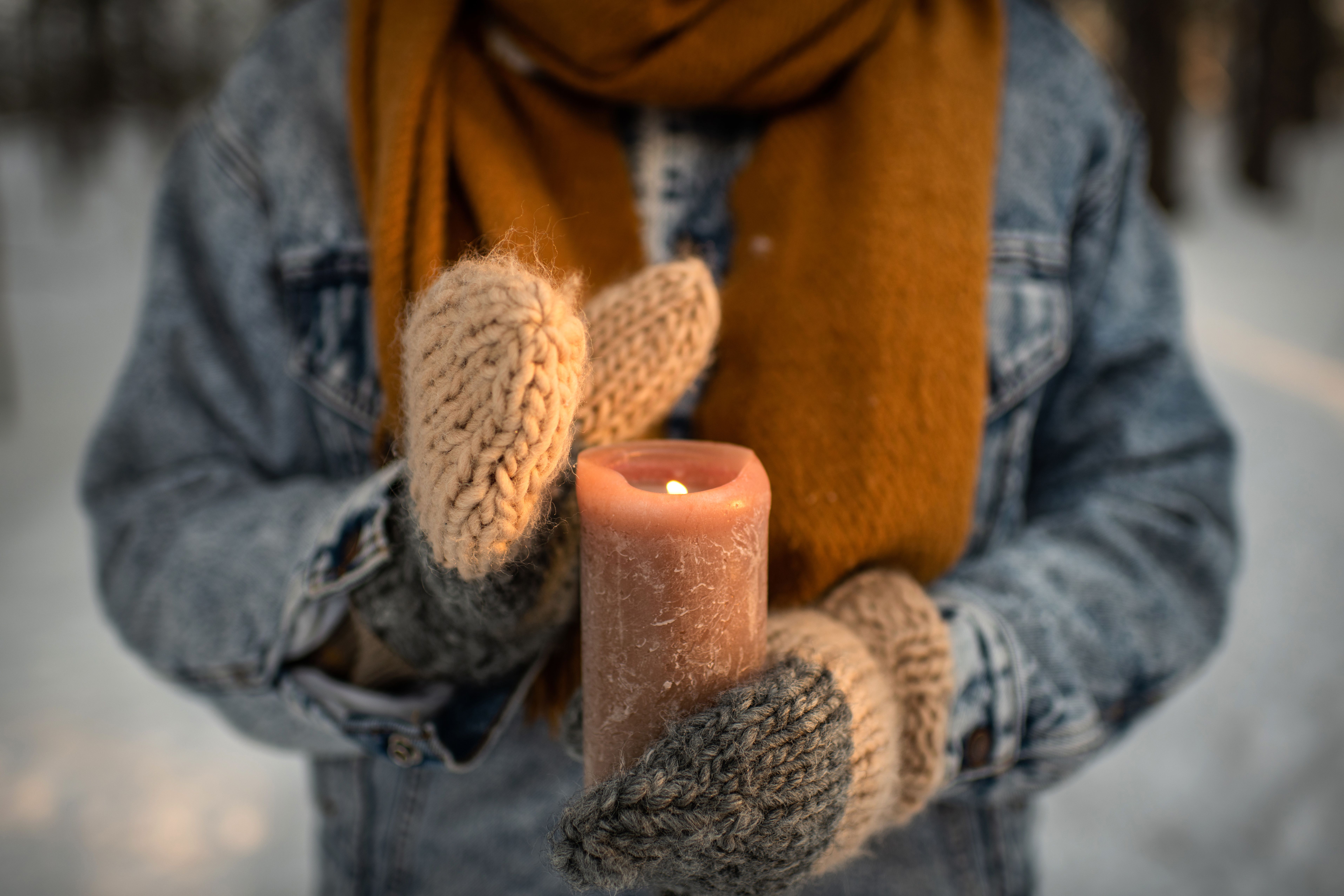 Tyttö kantaa palavaa kynttilää ulkona talvella